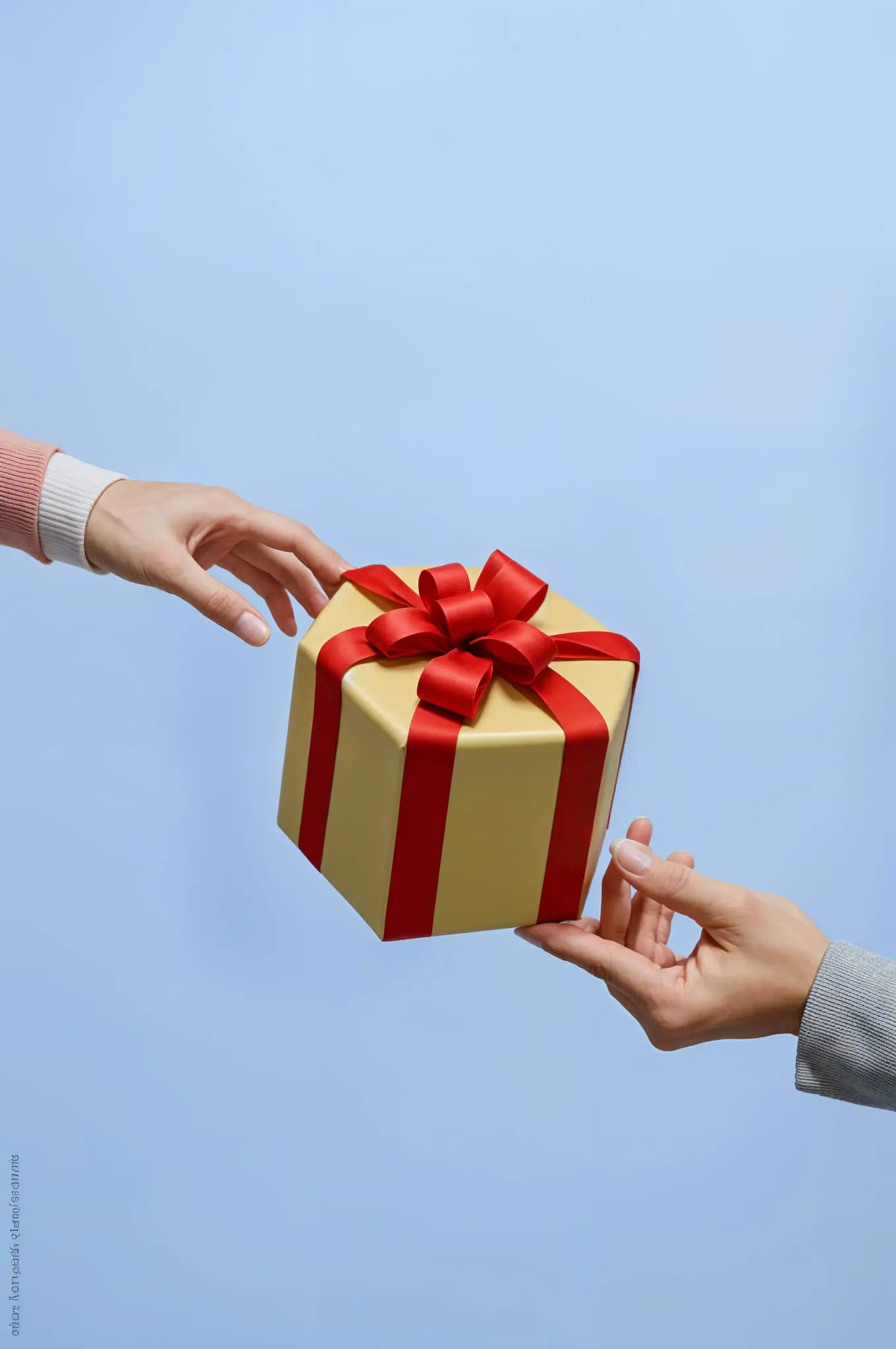 Un paquet cadeau au centre de l'image avec deux mains qui le rejoignent de part et d'autre de l'image, sur fond bleu clair