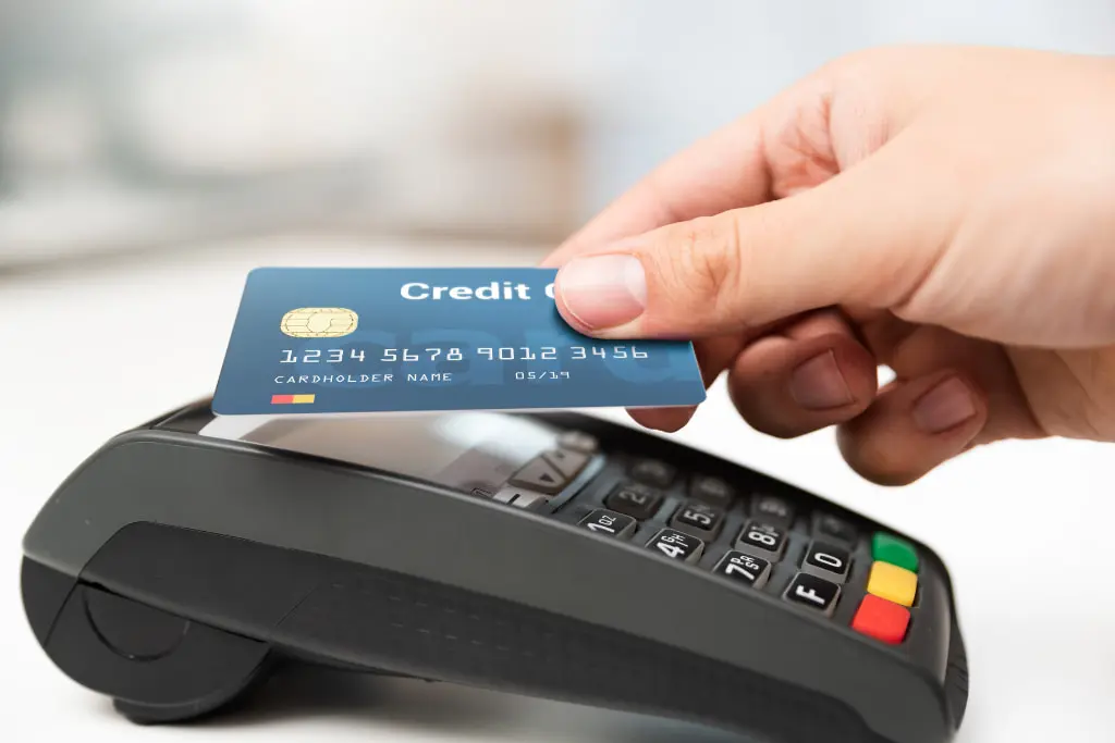 Une main dépose une carte bancaire sur un TPE pour effectuer un paiement sans contact