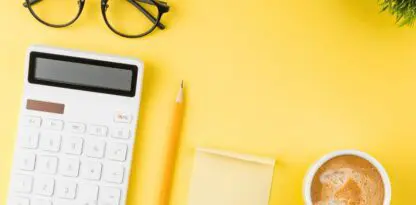 Sur fond jaune, plusieurs objets sont posés ; à gauche des lunettes de vue, une calculatrice et un crayon, au centre-bas un post-it et à gauche un café et dans le coin supérieur droit le feuillage d'une plante verte.