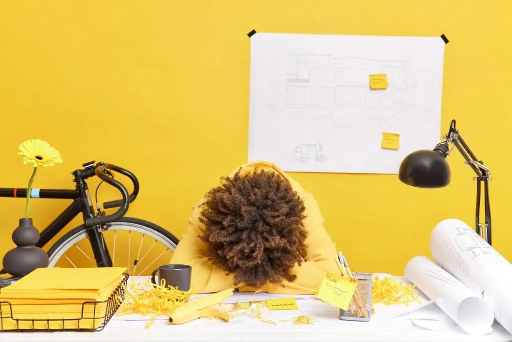 Sur fond jaune, une femme est affalée sur son bureau