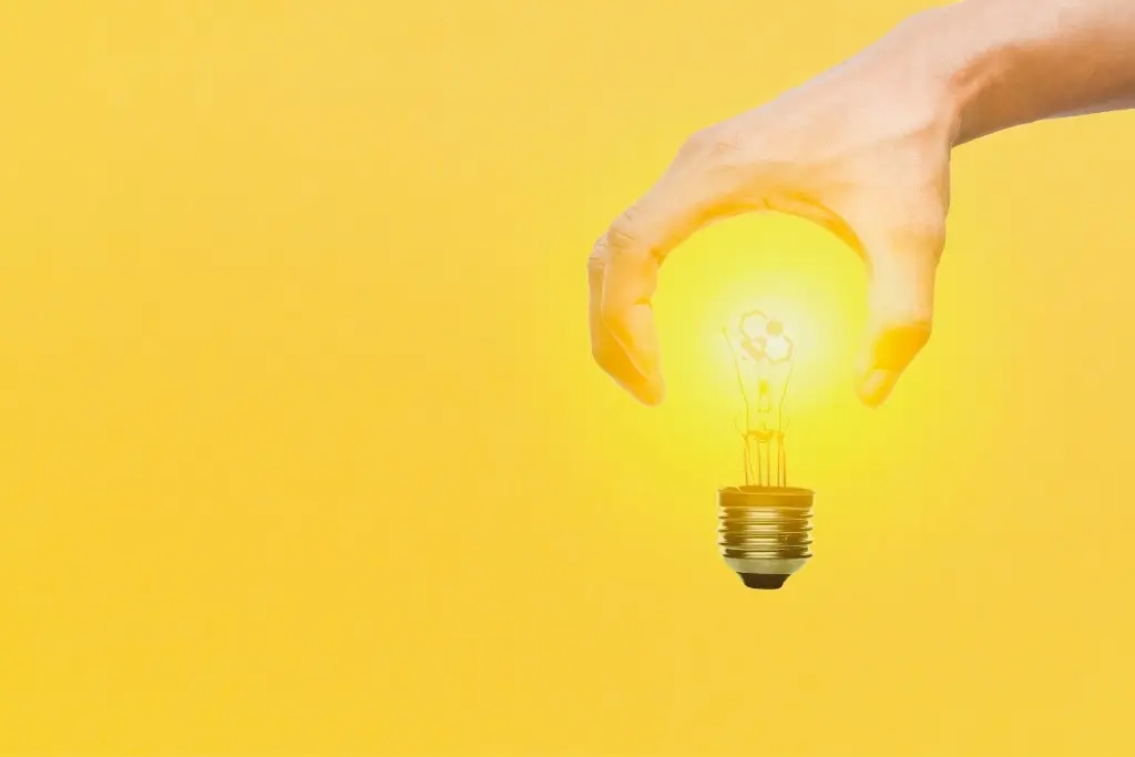 Sur fond jaune uni une main forme le dessus d'une ampoule et à l'intérieur on aperçoit le logo Olenbee