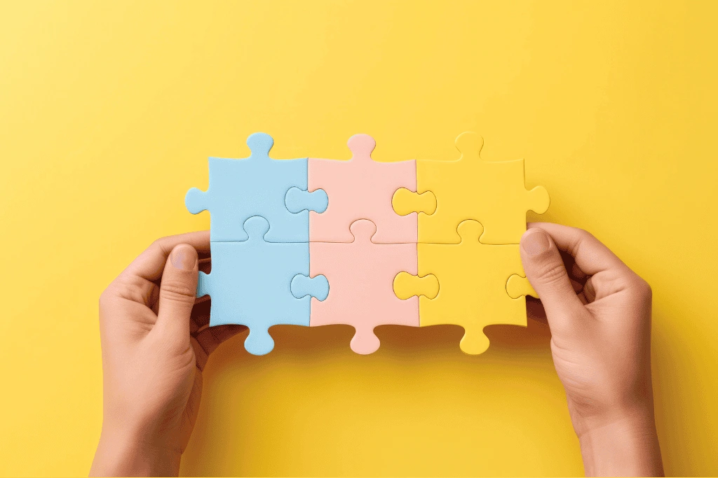 Sur fond jaune, deux mains tiennent des pièces de puzzle emboîtées