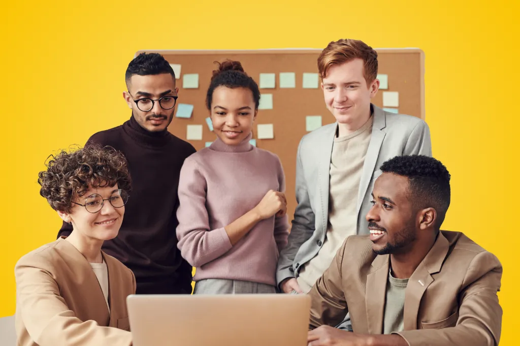 Sur fond jaune, une équipe de jeunes employés sont réunis devant un ordinateur, souriants