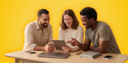 Sur fond jaune, une photographie candide d'une équipe souriante qui regardent une tablette, accoudés sur un bureau